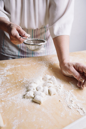 Front view of womans hands sprinkle with flour dough for meat dumplings.の写真素材
