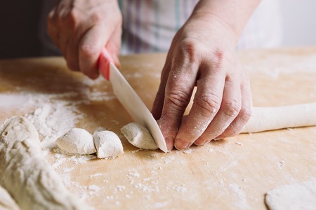 Close-up view of two womans hands cut knife dough for meat dumplings.の写真素材