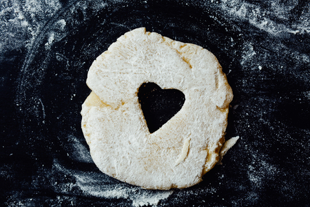 Small heart cut out of dough rolled on a table. Horizontal studio shot.の写真素材