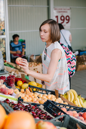 ARMAVIR, RUSSIA - JULE 9, 2017: Young woman standing near stall with fresh fruit and choosing.のeditorial素材