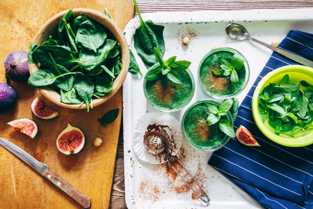 From above crop shot of green smoothies with leaves of fresh mint on the kitchen desk