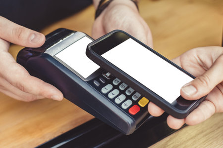 Person paying pay through smartphone using NFC technology in outdoor cafe.