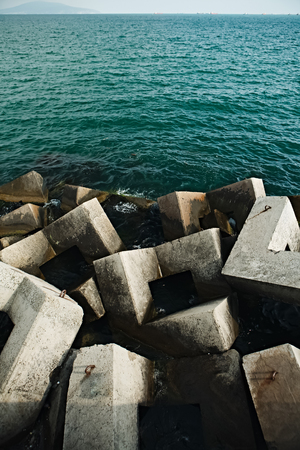 View of plenty of concrete blocks in water of sea creating breakwater on background of sea space.の写真素材