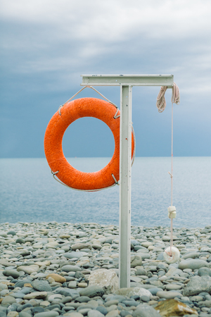 orange lifebuoy on the sea coast on cloudy dayの写真素材