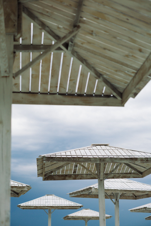 Wooden parasols and empty deckchairs on deserted beach on the off-season cloudy dayの写真素材