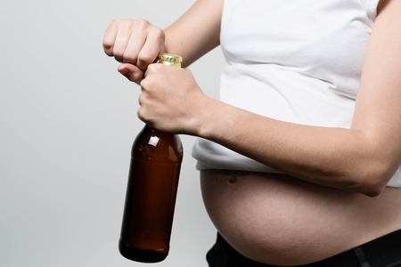 Anonymous pregnant woman opens beer bottleの写真素材