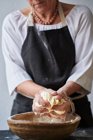 Slow motion shot of baker hands kneading dough in flour in wooden bowlの写真素材