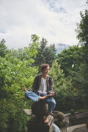 Relaxed preteen girl barefoot folded hand and meditating sitting on stony ball with crossed legsの写真素材