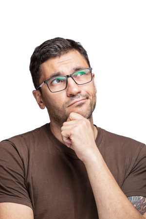 Crop shot of young handsome man with glasses wearing brown t-shirt over white background Thinking...