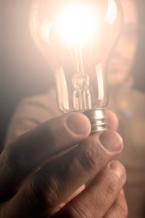 Mans hand holding lighted light bulb. Concept of idea with innovation and inspiration.