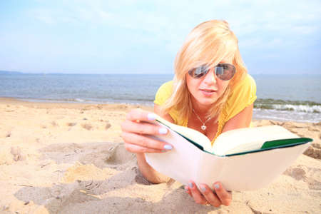 woman reading a book girl the yellow dress water beachの写真素材