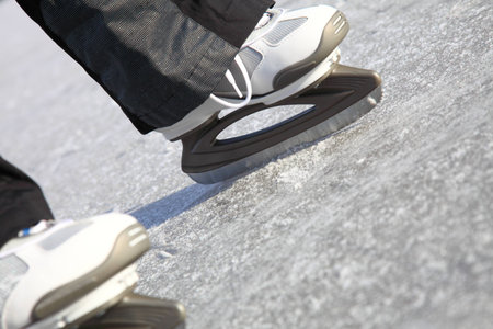 Young woman ice skating outdoors on a pond on a freezing winter day - detail of the legs