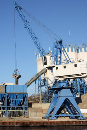 blue white crane unloading sand in a blue siloの写真素材