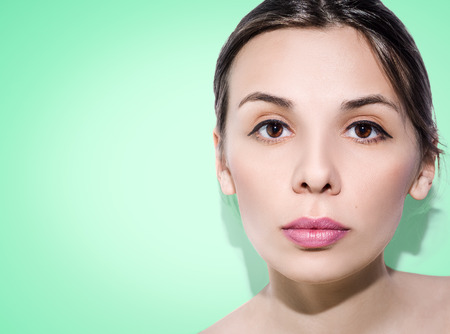 Woman with folded hair on green background. Nude make-up.の写真素材