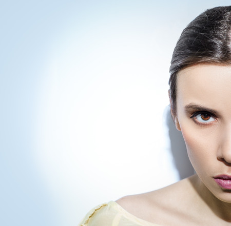 Half-faced woman on blue background. Angry face.の写真素材