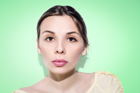 Woman with folded hair and concentrated eyeview on green background. Nude make-up.の写真素材