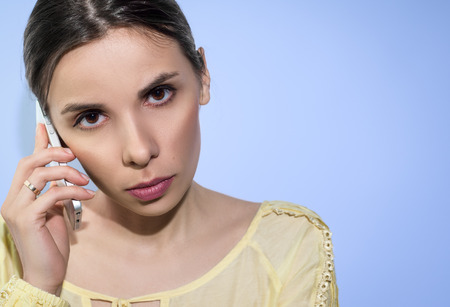 Woman, concentrated on conversation by phone. On blue background.の写真素材