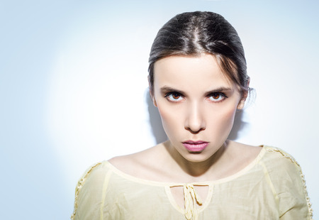 Annoyed, serious and a little angry woman on this pastel tone background. Minimum make-up, rose lips and yellow shirt.の写真素材
