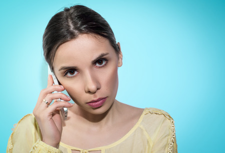 Woman, concentrated on conversation by phone. On blue background.の写真素材