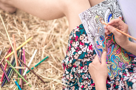 the girl sitting on the hay and coloring, with different bright pencils and slim legsの写真素材