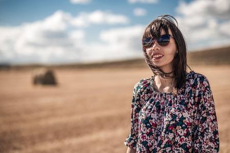 smiling girl with sunglasses in the field, beautiful sky, suuny dayの写真素材