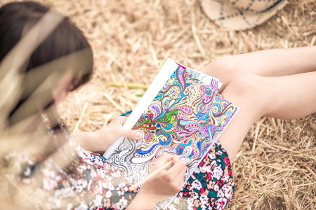 the brunette sitting on the hay and coloring, with different bright pencils and slim legs and hatの写真素材