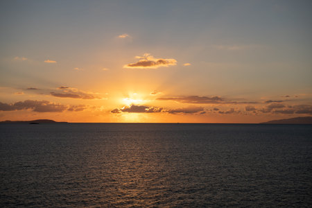 Sunset over the sea with clouds in the background.