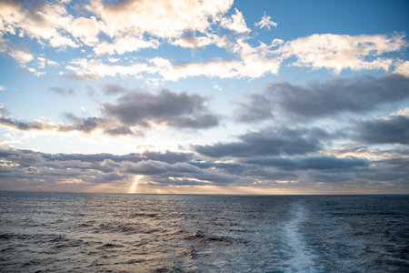 Sunset over the sea with clouds and rays of light passing through them.