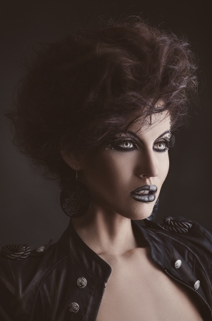 Portrait of a beautiful girl with a finger in the mouth with beautiful makeup and hairstyle on black background の写真素材