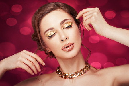 Beautiful girl with a gold chain around his neck, on a red background の写真素材