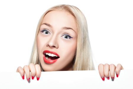 Blonde peeking out from behind a poster on which you can make advertising inscription or image の写真素材