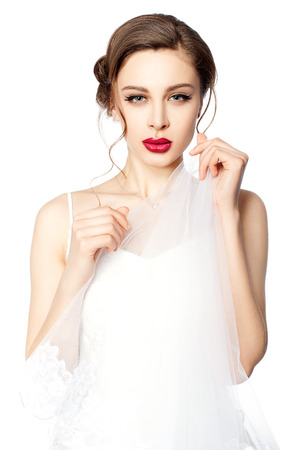 Portrait of a beautiful bride with red lips, she is holding a veil in her hands の写真素材