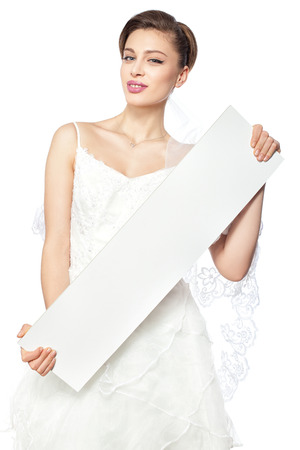 Laughing bride playfully shows a blank poster on which you can write an inscription の写真素材