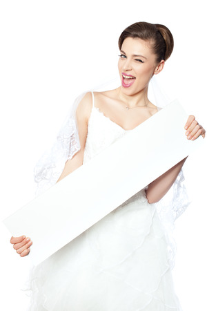 Joyful and happy bride shows a blank poster on which to make an inscription の写真素材
