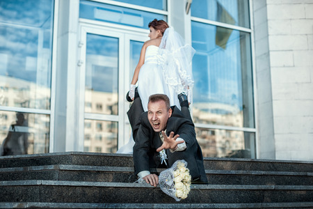 Bride groom grabbed his leg and pulls the wedding の写真素材