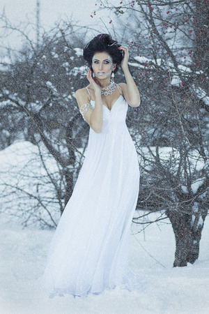 Girl in white dress standing in the snow の写真素材