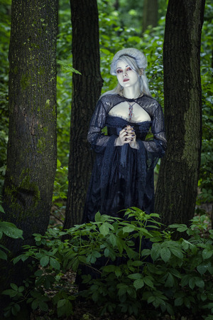 Beautiful young blond woman alone in the woods like a ghost の写真素材