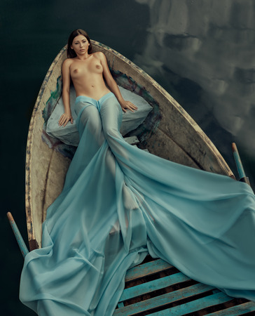 Beautiful naked girl in the boat like a mermaid の写真素材
