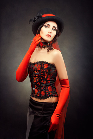 Portrait of a girl in a corset and top hat on his head showing retro style.の写真素材