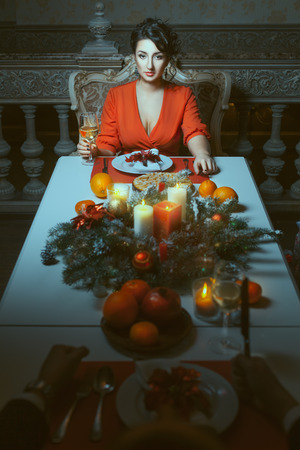 Young woman sitting at the banquet table in a bright red dress.の写真素材