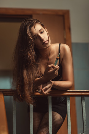 Girl addict with syringe is going to take the drug in the stairwell.の写真素材