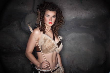 Girl with curly hair, dressed in amazon fur with a bow and arrow.の写真素材