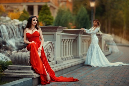 Girl in red park sits in the park. In the background is in Rasfokus bride like a dream.の写真素材