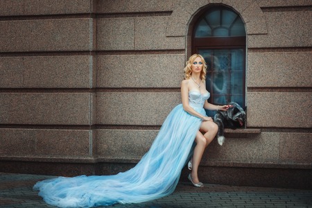Blonde girl in a blue long dress. Nearby sits the fox.の写真素材