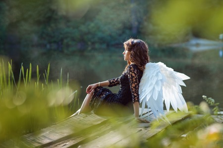 On the pier sits angel girl. Lake in the morning mist.の写真素材