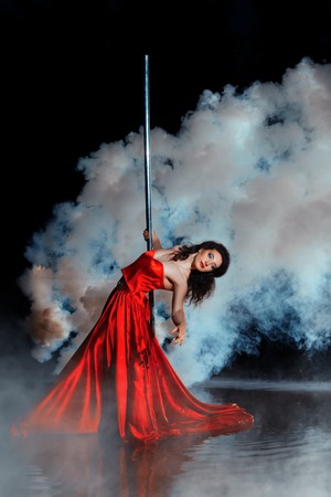 Girl shrouded in smoke dancing around a pole dance. See more images from this series.の写真素材