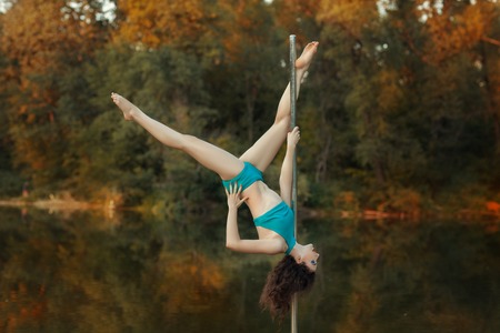 Girl does tricks on a pole dance. Around the beautiful forest and lake.の写真素材