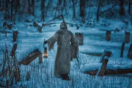 Figure of a man from the back with a scythe of death. He brings the horror and fear of death.の写真素材