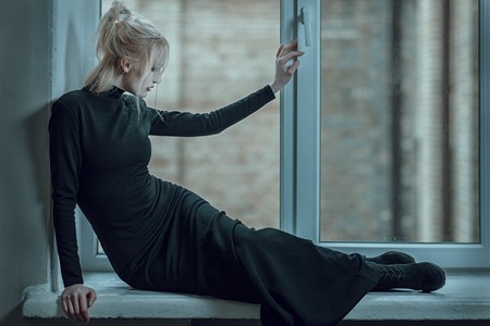 Blonde woman lying on the window sill and sad, her unhappy.の写真素材