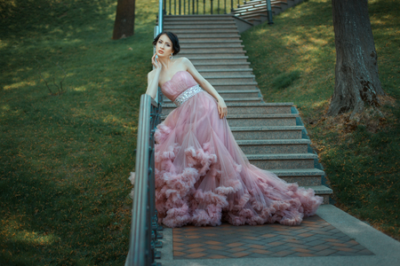 Girl in a magnificent pink dress with a train walking through the park.の写真素材